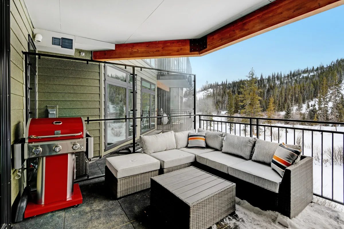 A private outdoor seating area with a grill set against the backdrop of scenic mountains. The patio is furnished for comfort and relaxation, perfect for enjoying a meal, morning coffee, or the sunset. The view captures fresh mountain air and the inviting atmosphere of alfresco living.