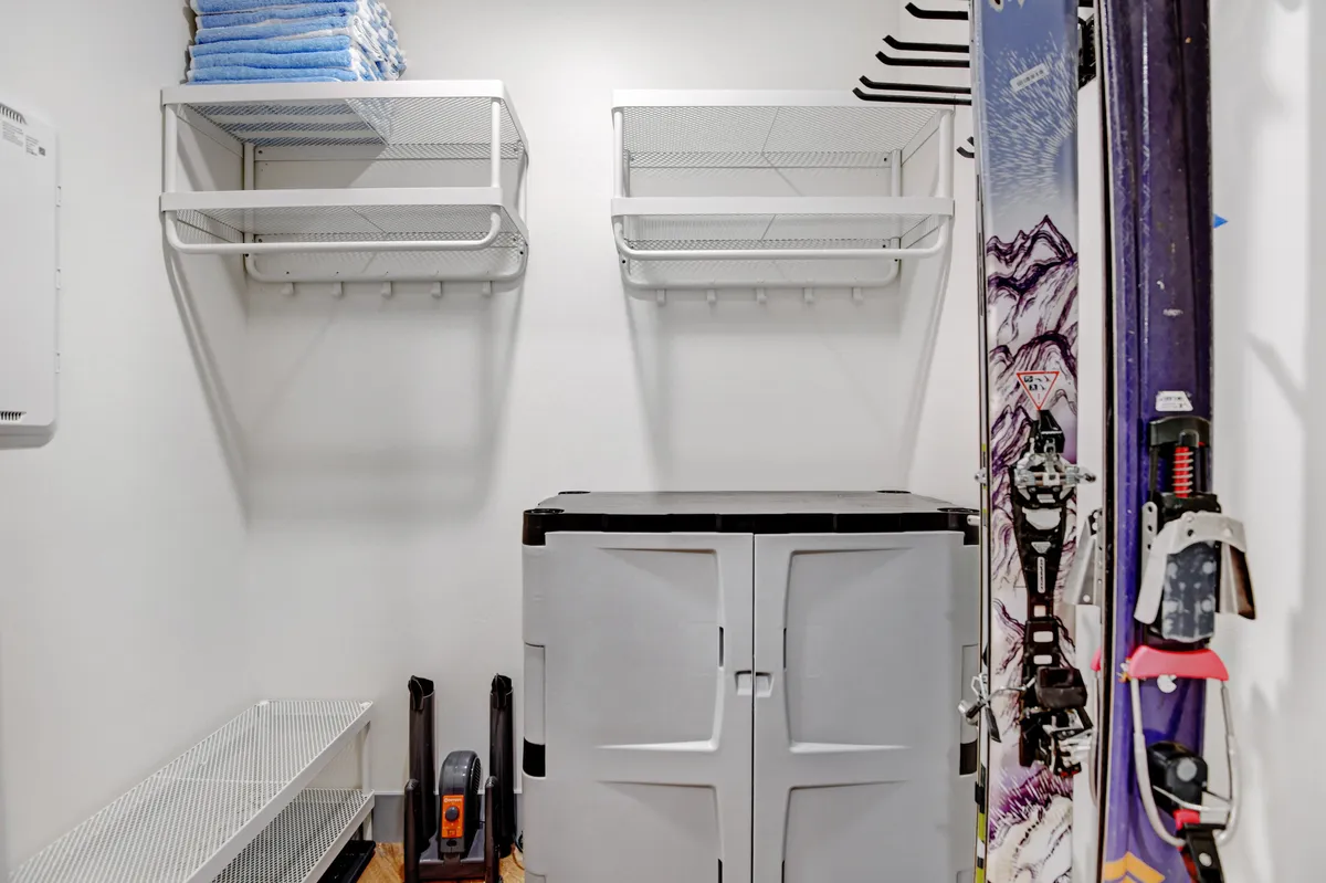 A practical shot of an in-unit storage area featuring ski equipment, storage units, and neatly folded towels. The space is organized, clearly dedicated to preparing and winding down from outdoor adventures.